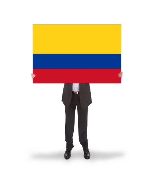 Empresario sosteniendo una tarjeta grande, bandera de Colombia — Foto de Stock