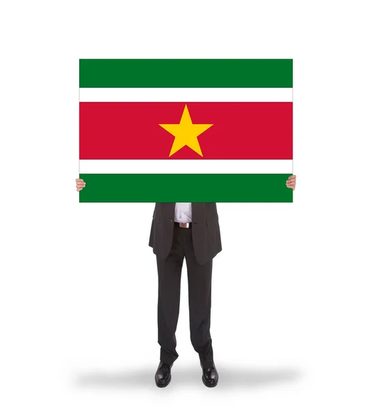 Empresario sosteniendo una gran tarjeta, bandera de Surinam — Foto de Stock