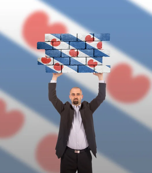 Businessman holding a large piece of a brick wall — Stock Photo, Image