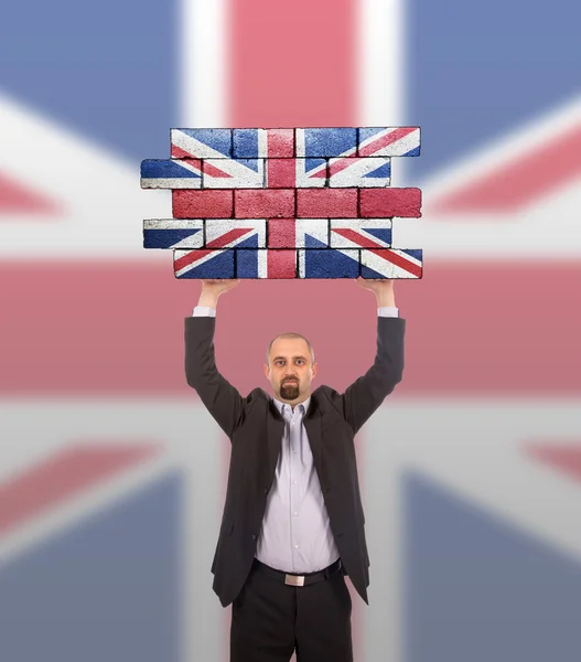 Businessman holding a large piece of a brick wall — Stock Photo, Image