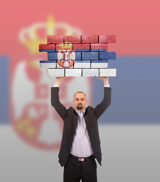 Homme d'affaires tenant un grand morceau d'un mur de briques — Photo