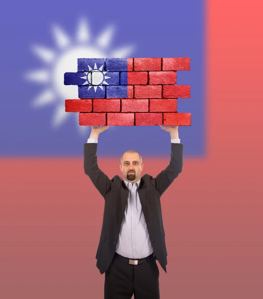 Businessman holding a large piece of a brick wall — Stock Photo, Image