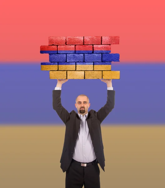 Geschäftsmann hält ein großes Stück einer Ziegelmauer — Stockfoto