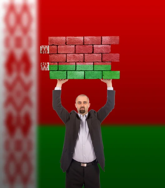 Businessman holding a large piece of a brick wall — Stock Photo, Image