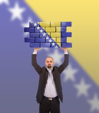 bir tuğla duvar büyük bir parçası tutan işadamı