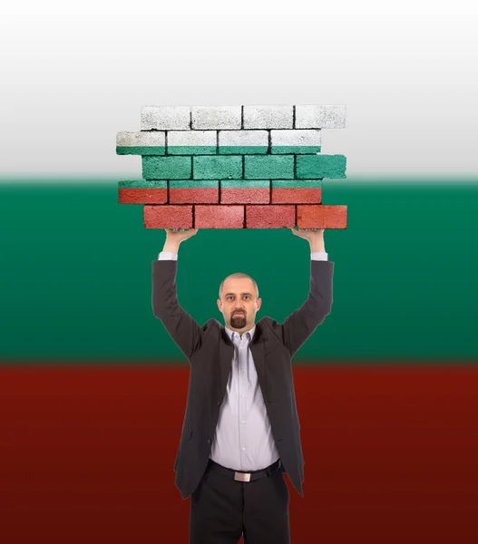 Zakenman die houdt een groot stuk van een bakstenen muur — Stockfoto