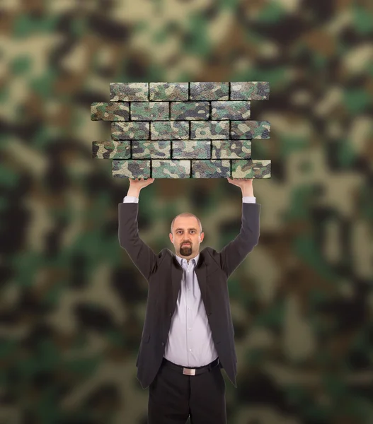 Uomo d'affari che tiene un grande pezzo di un muro di mattoni — Foto Stock