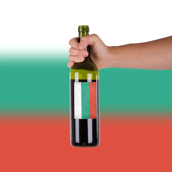 Mão segurando uma garrafa de vinho tinto — Fotografia de Stock