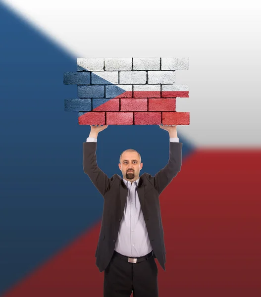 Businessman holding a large piece of a brick wall — Stock Photo, Image