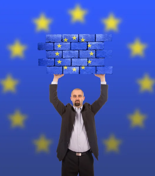 Businessman holding a large piece of a brick wall — Stock Photo, Image