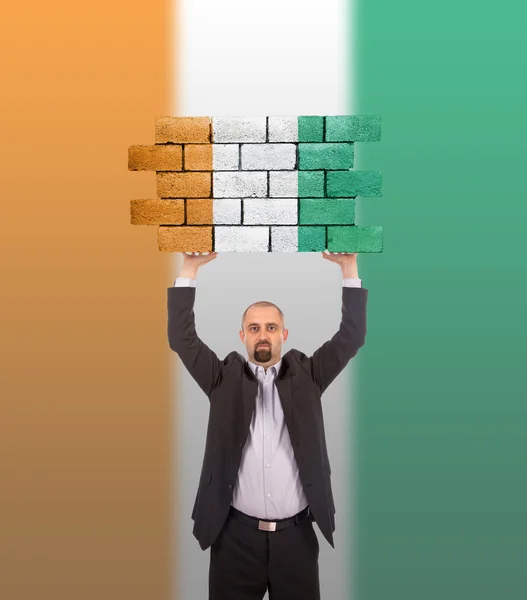 Businessman holding a large piece of a brick wall — Stock Photo, Image