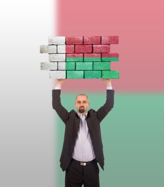 bir tuğla duvar büyük bir parçası tutan işadamı