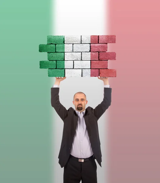 Empresario sosteniendo un pedazo grande de una pared de ladrillo — Foto de Stock