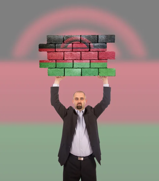 Businessman holding a large piece of a brick wall — Stock Photo, Image