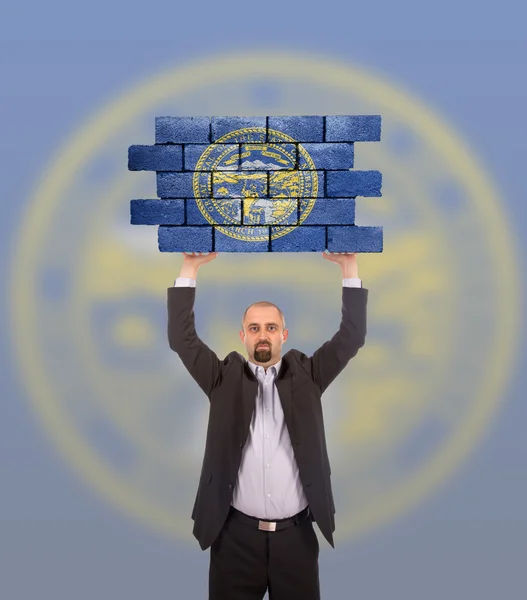 Businessman holding a large piece of a brick wall — Stock Photo, Image