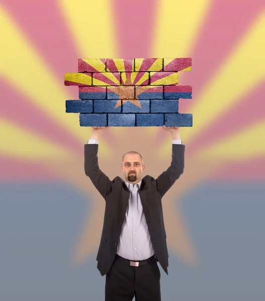 Homme d'affaires tenant un grand morceau d'un mur de briques — Photo