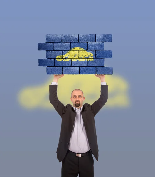 Businessman holding a large piece of a brick wall — Stock Photo, Image