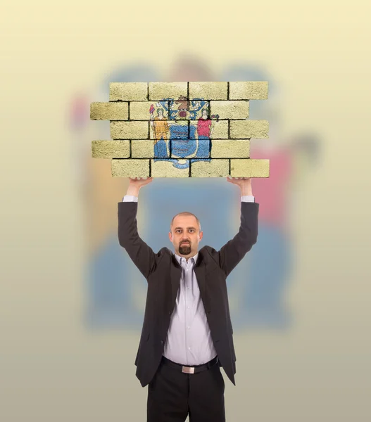 Бизнесмен держит в руках большой кусок кирпичной стены — стоковое фото