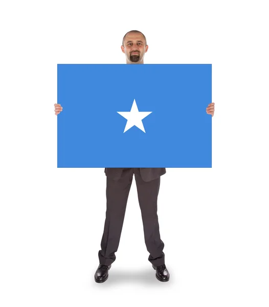 Smiling businessman holding a big card or flag — Stock Photo, Image