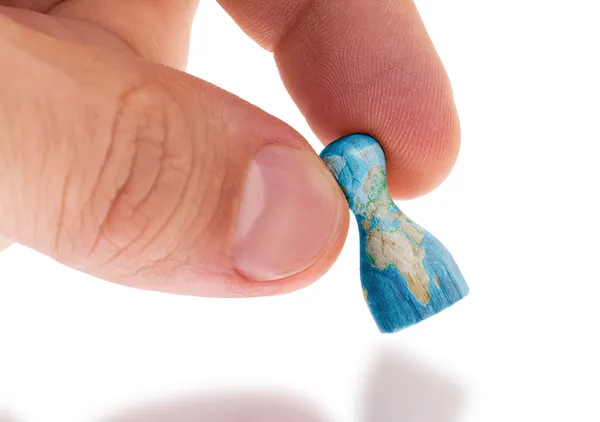 Hand holding wooden pawn, map painting, selective focus — Stock Photo, Image