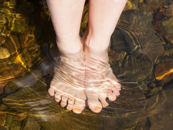 Dipping feet in water off a stone beach — Stock Photo, Image