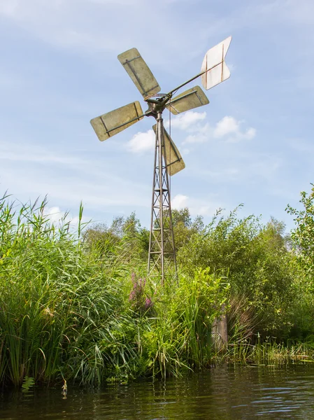 Маленькая и ржавая старая металлическая ветряная мельница у воды — стоковое фото