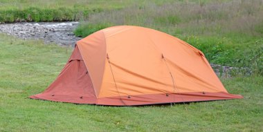 İzlanda 'daki kamp alanında yeşil çimlerin üzerine turuncu kubbe.