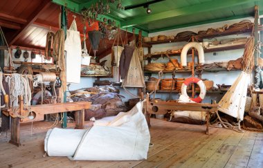 Bir gemi için eski yelkenler ve iplerle dolu ahır.