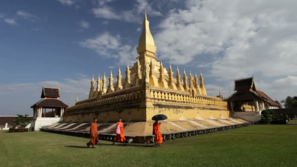Tres monjes caminando frente a la pagoda dorada, Laos — Vídeo de stock