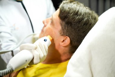 Yakından yakışıklı bir adam cilt sağlığını canlandırmak için renkli ışık terapisi görüyor..