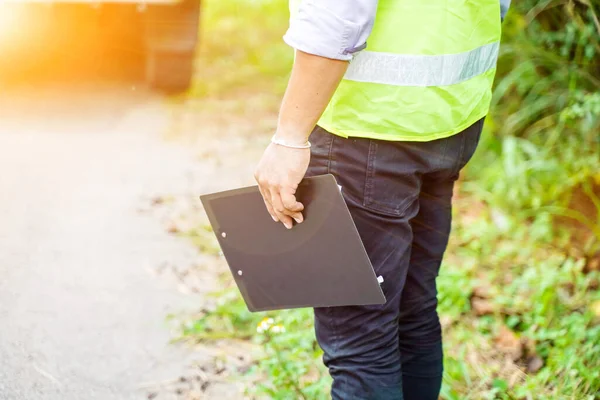 Closeup and crop insurance employee or service man holding a clipboard at locale with sun and lens flare background.