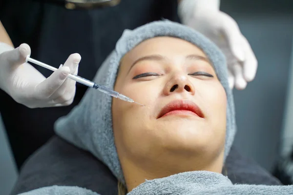 Closeup and crop hands of beauty doctor in medical grove holding beauty skin syringe injecting the customer\'s face. Beauty skin concept