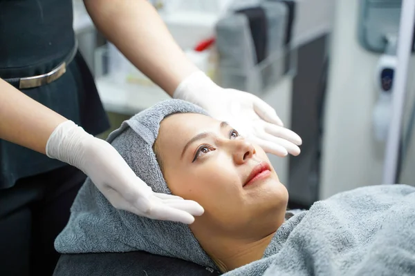 Closeup beauty nurse show of face scrub cream on hands before making facial massage with organic face scrub on customer face.