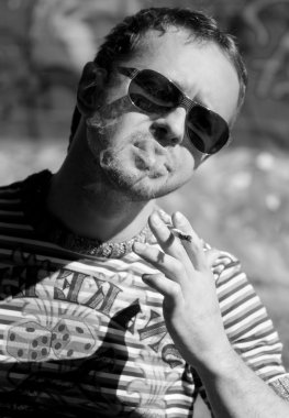 Genç adam sigara içiyor.