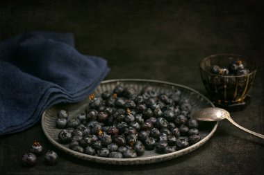 Koyu arkaplanda bir tepside çiğ yaban mersini.