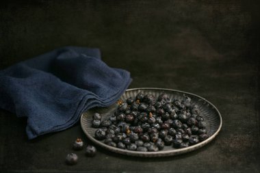 Koyu arkaplanda bir tepside çiğ yaban mersini.