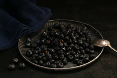 Koyu arkaplanda bir tepside çiğ yaban mersini.