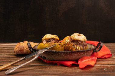 Giraumon veya ahşap bir masada eski bir tabakta etle doldurulmuş türbanlı balkabağı.