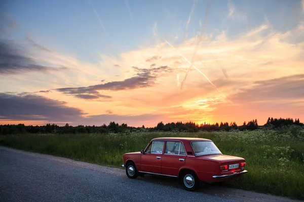 レッドソビエト車Vaz 2101はピンクの夏の夕日を背景にフィールドの隣の道路に立っています ロシア夏 — ストック写真