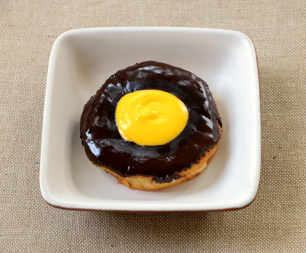 Chocolate donut on plate isolated on a fabric — Stock Photo, Image