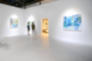 Sanat sergisi galerisindeki beyaz duvardaki resimlere bakıyorlar. Bulanık arkaplan.