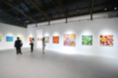 Sanat sergisi galerisindeki beyaz duvardaki resimlere bakıyorlar. Bulanık arkaplan.