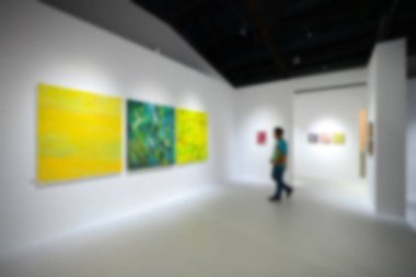 Sanat sergisi galerisindeki beyaz duvardaki resimlere bakıyorlar. Bulanık arkaplan.