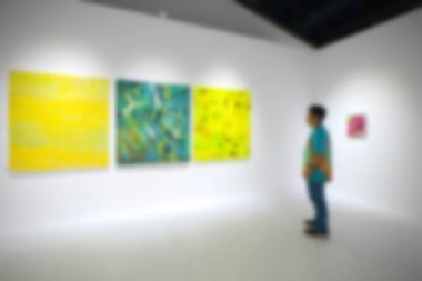 Sanat sergisi galerisindeki beyaz duvardaki resimlere bakıyorlar. Bulanık arkaplan.