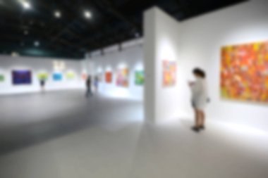Sanat sergisi galerisindeki beyaz duvardaki resimlere bakıyorlar. Bulanık arkaplan.