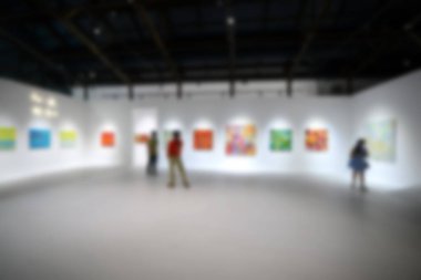 Sanat sergisi galerisindeki beyaz duvardaki resimlere bakıyorlar. Bulanık arkaplan.