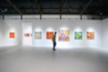 Sanat sergisi galerisindeki beyaz duvardaki resimlere bakıyorlar. Bulanık arkaplan.