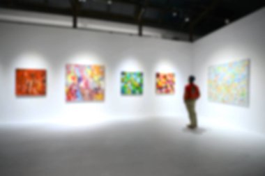 Sanat sergisi galerisindeki beyaz duvardaki resimlere bakıyorlar. Bulanık arkaplan.