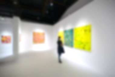 Sanat sergisi galerisindeki beyaz duvardaki resimlere bakıyorlar. Bulanık arkaplan.