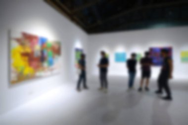Sanat sergisi galerisindeki beyaz duvardaki resimlere bakıyorlar. Bulanık arkaplan.